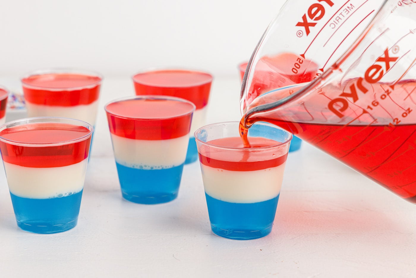 pouring red jello on top of blue and white