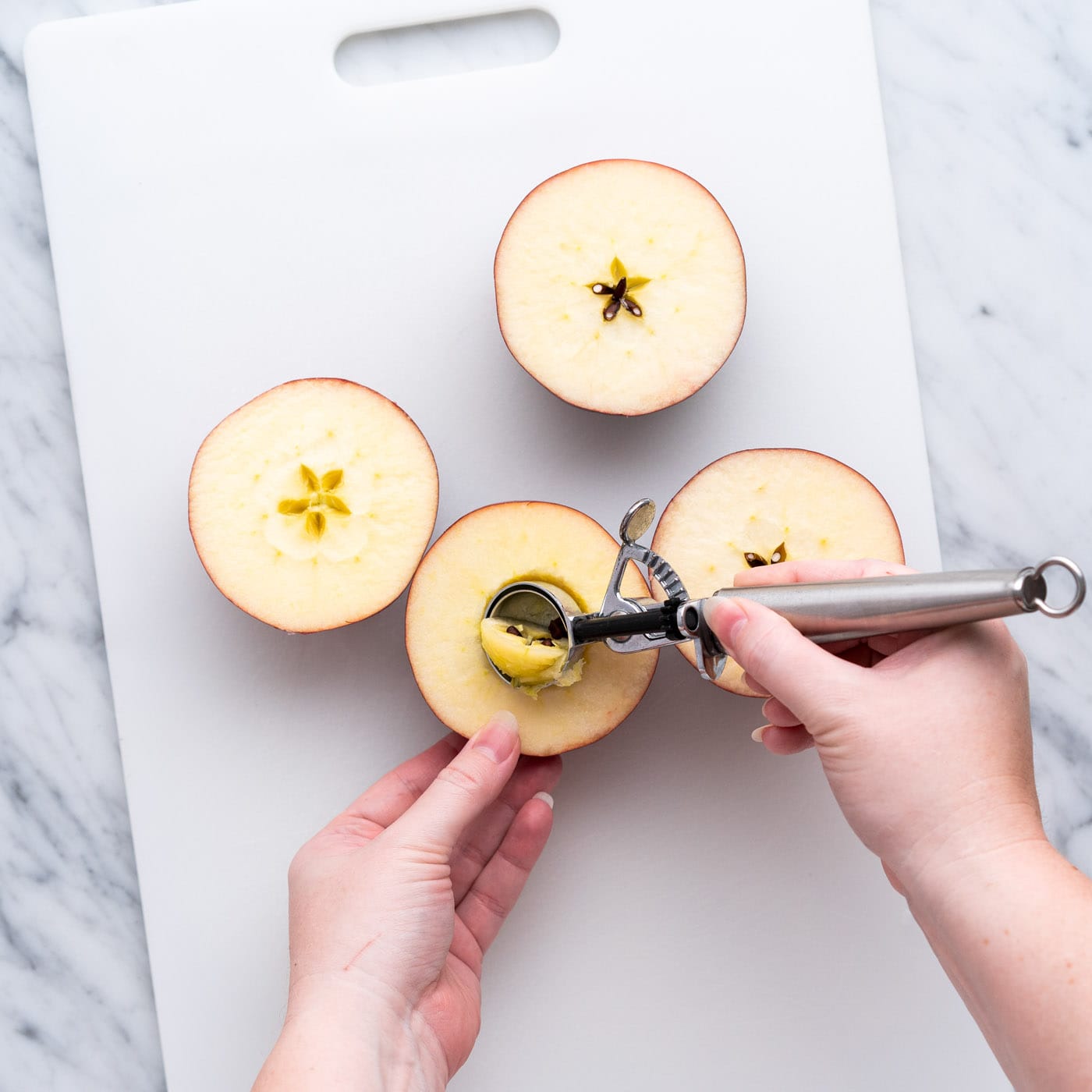 coring apple halves on cutting board