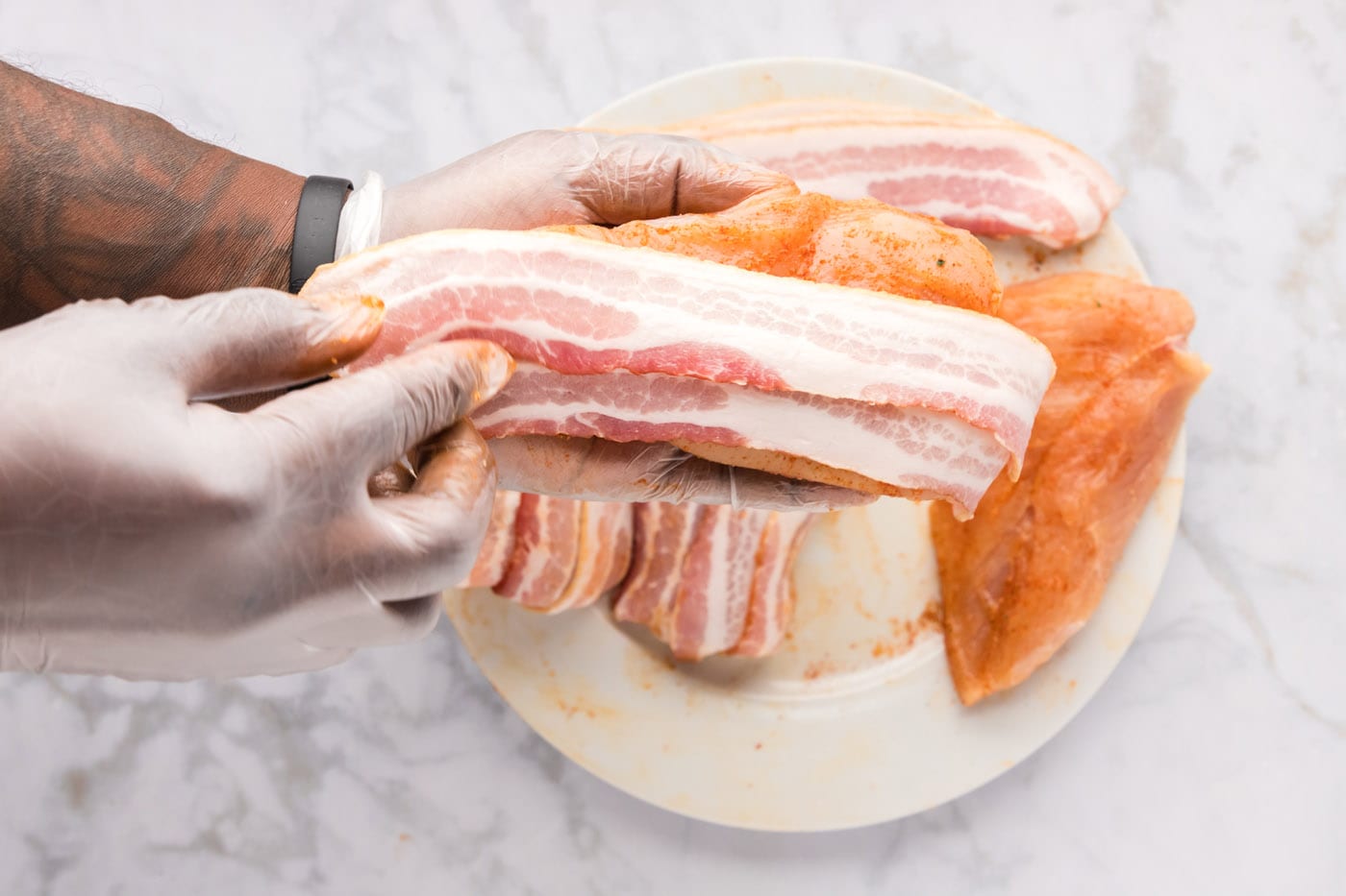 bacon strips on top of seasoned chicken breasts