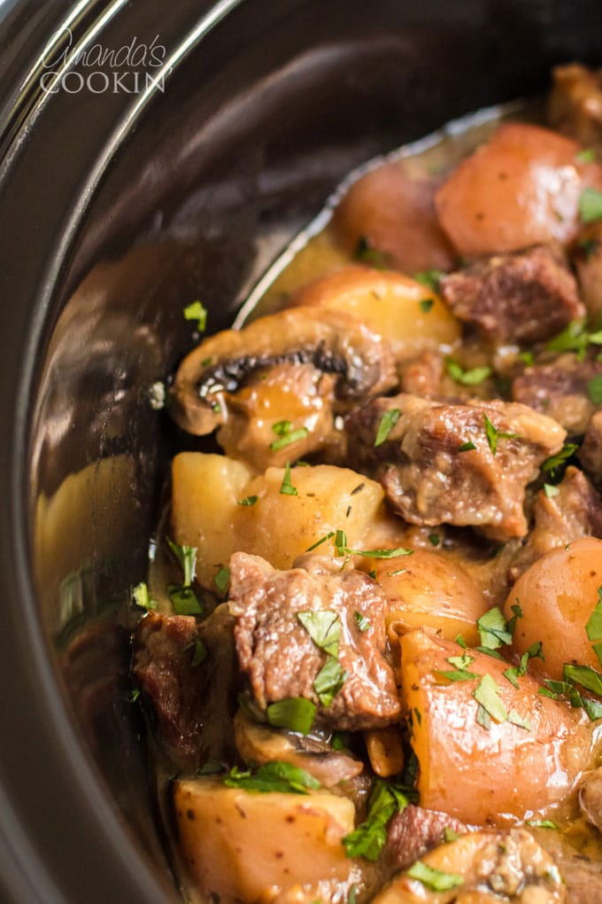 close up of beef stew in a black crockpot 