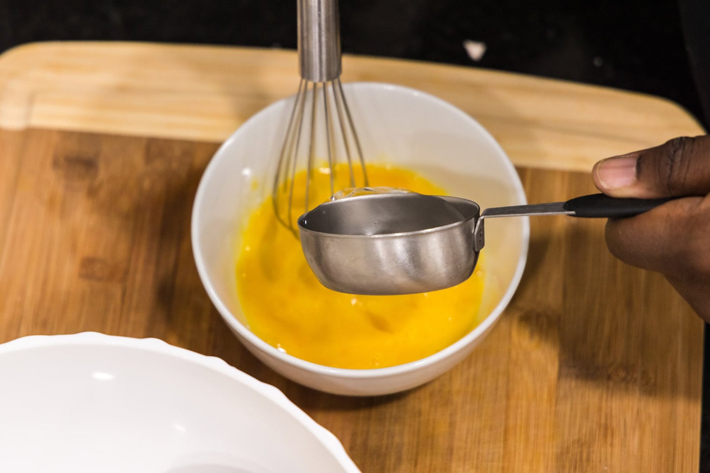 adding water to bowl with whisked eggs