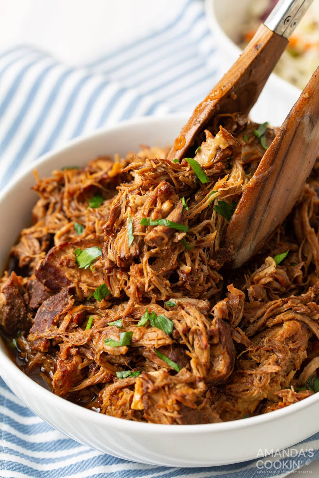 tongs in a bowl of Instant Pot Pulled Pork