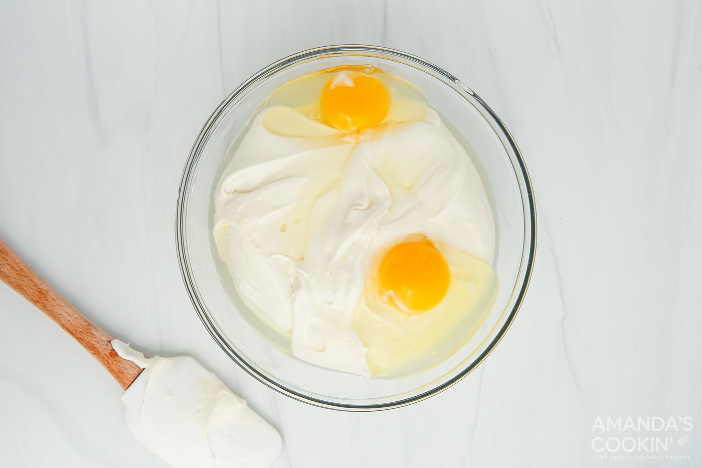 eggs in a mixing bowl with cream cheese and sour cream mixture