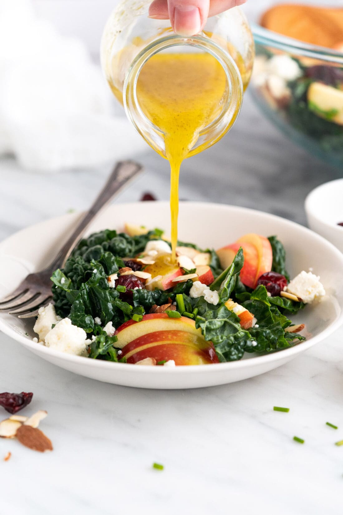 Fresh lemon dressing being drizzled over a bowl of Kale Salad