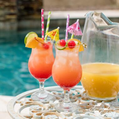 two glasses of rum punch poolside with a pitcher