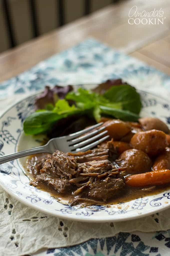 crockpot roast beef on a plate with carrots and salad